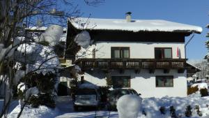 una casa cubierta de nieve con coches aparcados delante en Haus Obermoser, en Kitzbühel