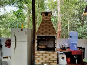 a kitchen with a pizza oven next to a refrigerator at Cabana do Tarzan na Praia de Parati Mirim in Paraty