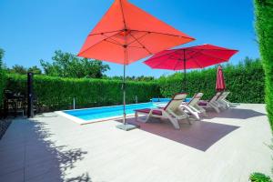 een groep stoelen en parasols naast een zwembad bij MY DALMATIA - Apartment ViGo with private pool in Bokanjac