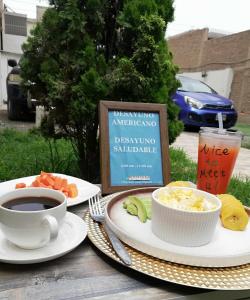 a table with two plates of food and a cup of coffee at Hotel Villa Capricce in Puente Piedra +20 photos