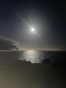 una luna llena elevándose sobre el agua por la noche en Between Mountain and Sea, en Ciudad del Cabo