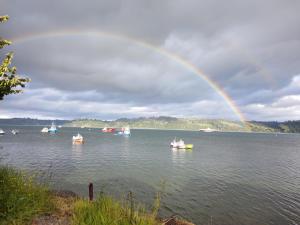 un arco iris sobre un lago con barcos en el agua en Departamento Refugio Compinches, Castro Chiloé, en Tentén