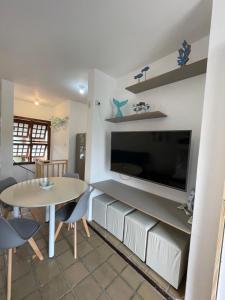 a living room with a tv and a table with chairs at Pé na Areia na Praia das Toninhas - Villagio 24 Porto Feliz in Ubatuba