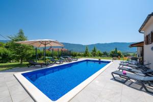 a swimming pool with chairs and an umbrella at Activity and familiy Villa Milena with heated pool in Kršan