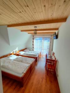 a bedroom with two beds and a table and a window at Willa WIDOKOWA CUDZICH in Zakopane
