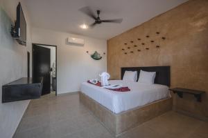 a bedroom with a large white bed and a ceiling at Hotel Kuxtal in Valladolid