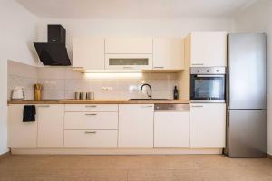 a kitchen with white cabinets and a stainless steel refrigerator at MY DALMATIA - Holiday home Agro Casa with private heated pool in Skradin