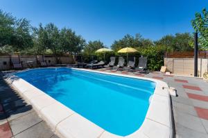 una piscina con sedie e ombrelloni di MY DALMATIA - Holiday home Olive Garden with private swimming pool a Lađevci