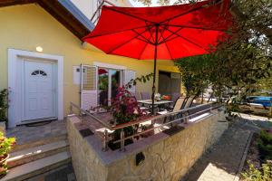 un ombrello rosso seduto sopra un patio di MY DALMATIA - Holiday home Olive Garden with private swimming pool a Lađevci