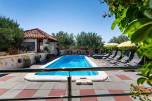 una piscina con sedie e ombrelloni su un patio di MY DALMATIA - Holiday home Olive Garden with private swimming pool a Lađevci