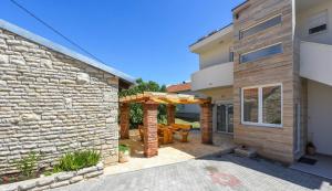 a house with a stone wall and a patio at MY DALMATIA - Sea view villa Possedaria with amazing roof terrace in Posedarje