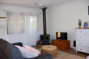 a living room with a couch and a stove at Bluebell Cottage in Beechmont