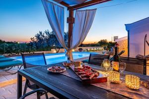 a table with a plate of food on it next to a pool at MY DALMATIA - Villa Elia with private pool and panoramic sea view in Zadar