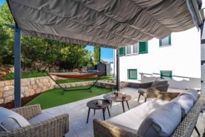 a patio with chairs and a hammock under a large umbrella at MY DALMATIA - Sea view villa Nana with private swimming pool in Lukoran