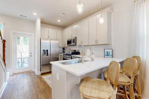 una cucina con armadi bianchi e un'isola cucina con sedie di Mini Manor off Meeting a Charleston