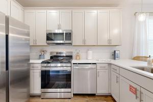 una cucina con mobili bianchi e un frigorifero in acciaio inossidabile di Mini Manor off Meeting a Charleston Altre 16 foto