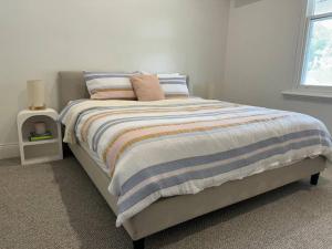 un letto con coperta a righe e cuscini sopra di Baxter Cottage a Bendigo