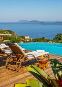 a pair of chairs sitting on a deck next to a pool at Gringos Boutique Hotel in Búzios