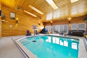 a large swimming pool in a room with a wooden ceiling at 6BR Houghton Lake House with Indoor Pool, Hot Tub and Golf Simulator in Prudenville
