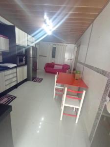Una cocina con una mesa roja y un sofá rojo. en Residencial Roseleia, en Penha
