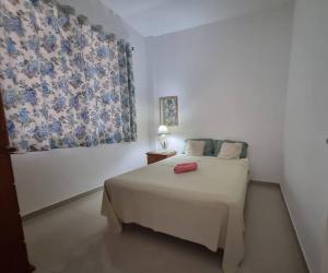 a bedroom with a bed with a red object on it at Excepcional apartamento central e perto da praia in Cabo Frio