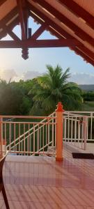 eine Veranda mit einem weißen Geländer und einer Palme in der Unterkunft HAUT DE VILLA VU SUR LA MONTAGNE. in Saint-Louis