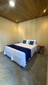 Cette chambre comprend un grand lit avec des draps bleus et blancs. dans l'établissement Pousada Oiti, à Barrinha 17 autres photos