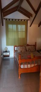 ein Holzbett in einem Zimmer mit Fenster in der Unterkunft HAUT DE VILLA VU SUR LA MONTAGNE. in Saint-Louis