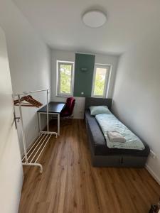 City-Krefeld Luxus 3 Zimmer Apartment mit Balkon في كريفيلد: غرفة نوم صغيرة بها سرير ومكتب