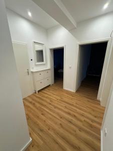 City-Krefeld Luxus 3 Zimmer Apartment mit Balkon في كريفيلد: غرفة فارغة بجدران بيضاء وأرضية خشبية