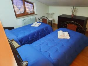 two beds in a room with blue sheets at Appartamento Rosanna in Spoleto