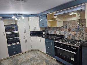 Una cocina con gabinetes blancos y electrodomésticos negros. en Apartment, en Seis de Octubre