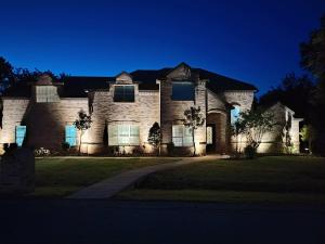a large brick house at night with a driveway at Shady Shores Lake House - Hot Tub Dog-Friendly in Shady Shores