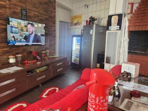 a living room with a red couch and a tv at Pousada do sossego mar e verde 1,2 e 3 in Itanhaém