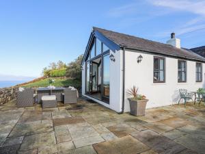 ein Haus mit einer Terrasse mit Tisch und Stühlen in der Unterkunft Tai Ffolt in Pwllheli