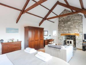 ein Schlafzimmer mit einem weißen Bett und einem Steinkamin in der Unterkunft Tai Ffolt in Pwllheli