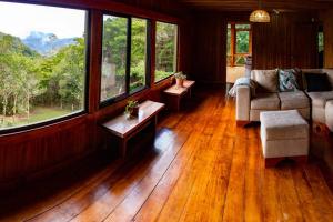 a living room with wood floors and windows and a couch at Private House Next to the Cloud Forest Reserve in Monteverde Costa Rica +24 photos