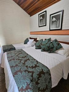 two beds in a hotel room with two bedsvisor at Pousada Recanto João de Barro in Cunha