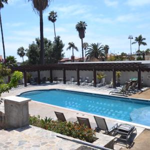 a swimming pool with chairs and palm trees at Hotel Quintas Papagayo in Ensenada +26 photos
