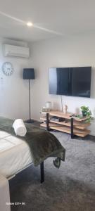 a bedroom with a bed and a flat screen tv at CBD Upstairs Studio Apartment in Christchurch