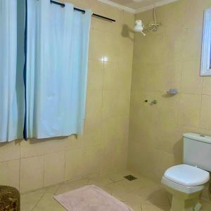 La salle de bains est pourvue d'une douche, de toilettes et d'un rideau de douche. dans l'établissement Casa confortável e espaçosa em Búzios, à Armacao dos Buzios