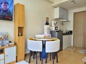 a kitchen with a table and some white chairs at Auberge Condotels at SMDC Hope Residences in Trece Martires