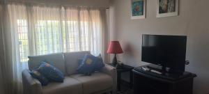 Una sala de estar con un sofá y un televisor de pantalla plana. en Alelur, en La Paloma