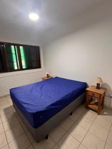 a bedroom with a blue bed and two tables at Praia Enseada Apartamento entre Praias in Ubatuba +9 photos