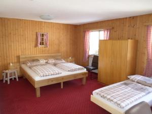 una camera da letto con due letti e una sedia di Hotel Mira a Sedrun