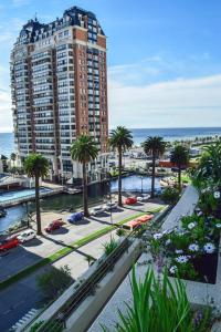 un grand bâtiment avec des palmiers et l'océan dans l'établissement Departamento Viña del Mar Coraceros, à Viña del Mar