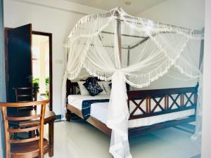 a canopy bed with white curtains in a bedroom at VOGEL NEST in Midigama East