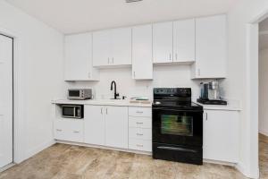 a kitchen with white cabinets and black appliances at Relaxing 3-Bedroom With 150 Inch Projector & Pool Table in Jacksonville