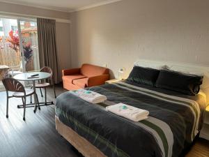 a bedroom with a bed and a chair and a table at Ulladulla Harbour Motel in Ulladulla +60 photos