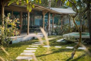 a house with a stone path in the yard at Villa Harimau-Original Joglo style 3B with pool in Gili Trawangan